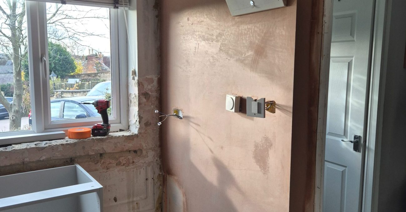 Part-plastered kitchen walls, a new base cabinet and an electrical consumer unit during the Stamford renovation.